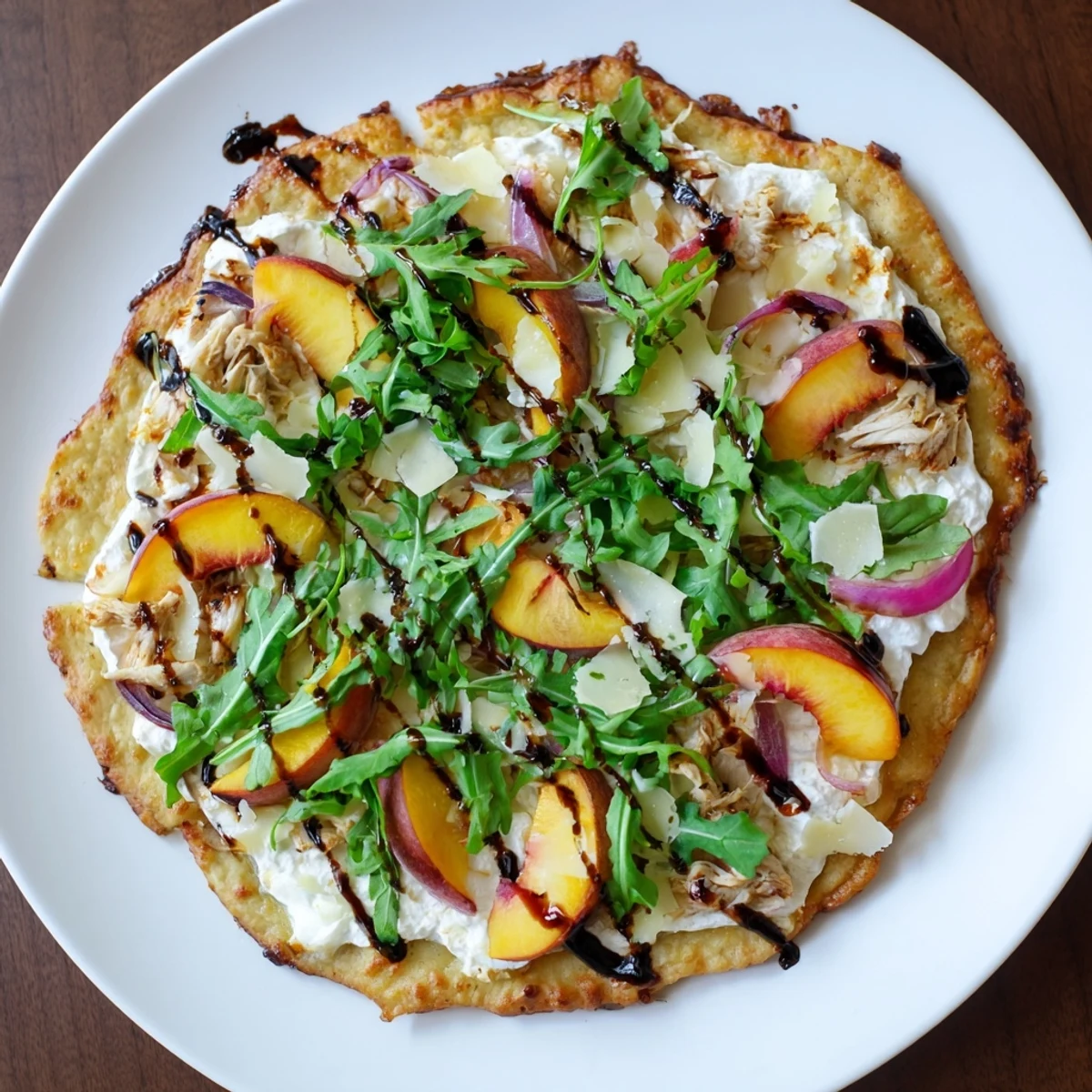 Summer pizza featuring juicy peaches, chicken, and creamy ricotta with crisp arugula garnish