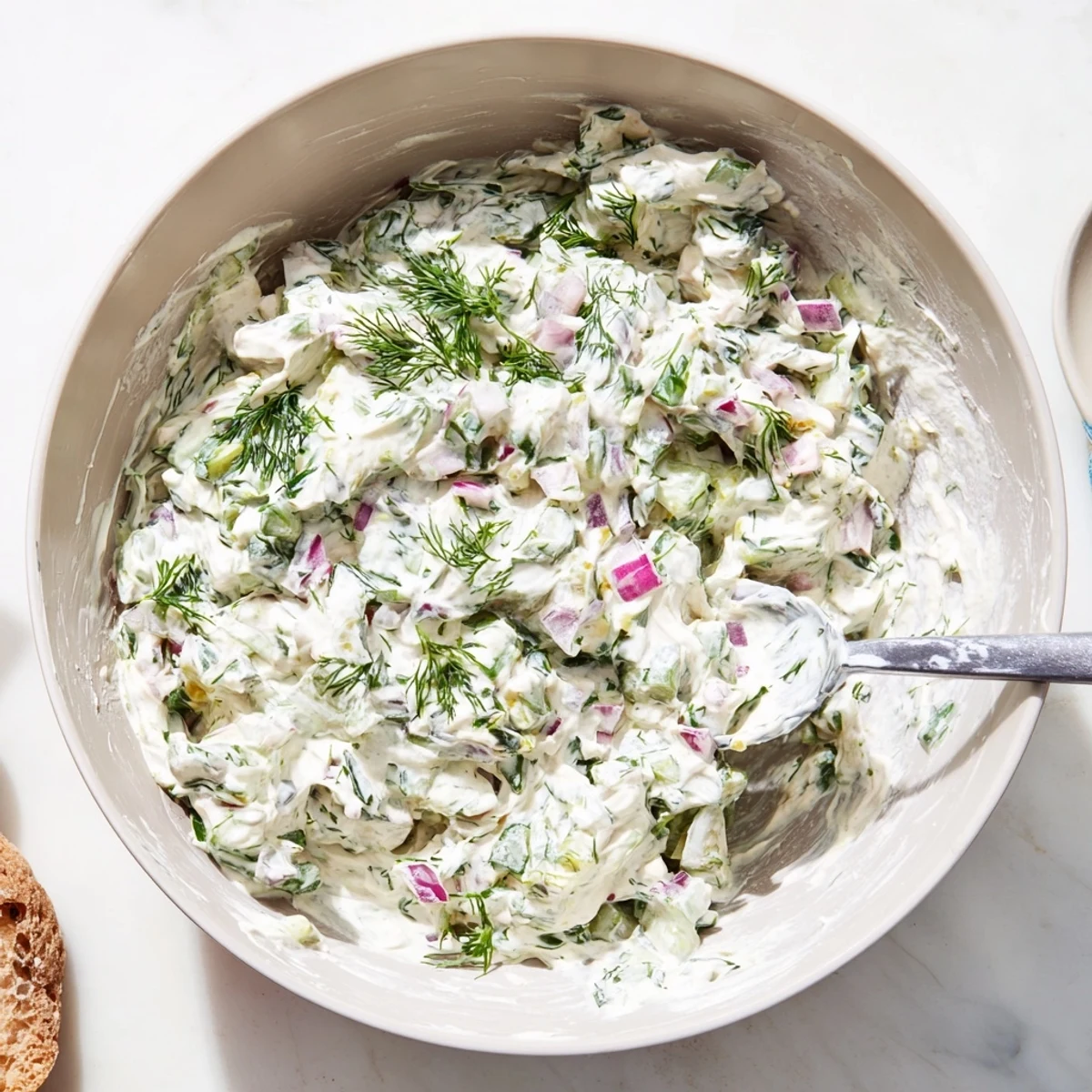 Thick white spicy dill pickle sauce dolloped onto a wooden serving spoon