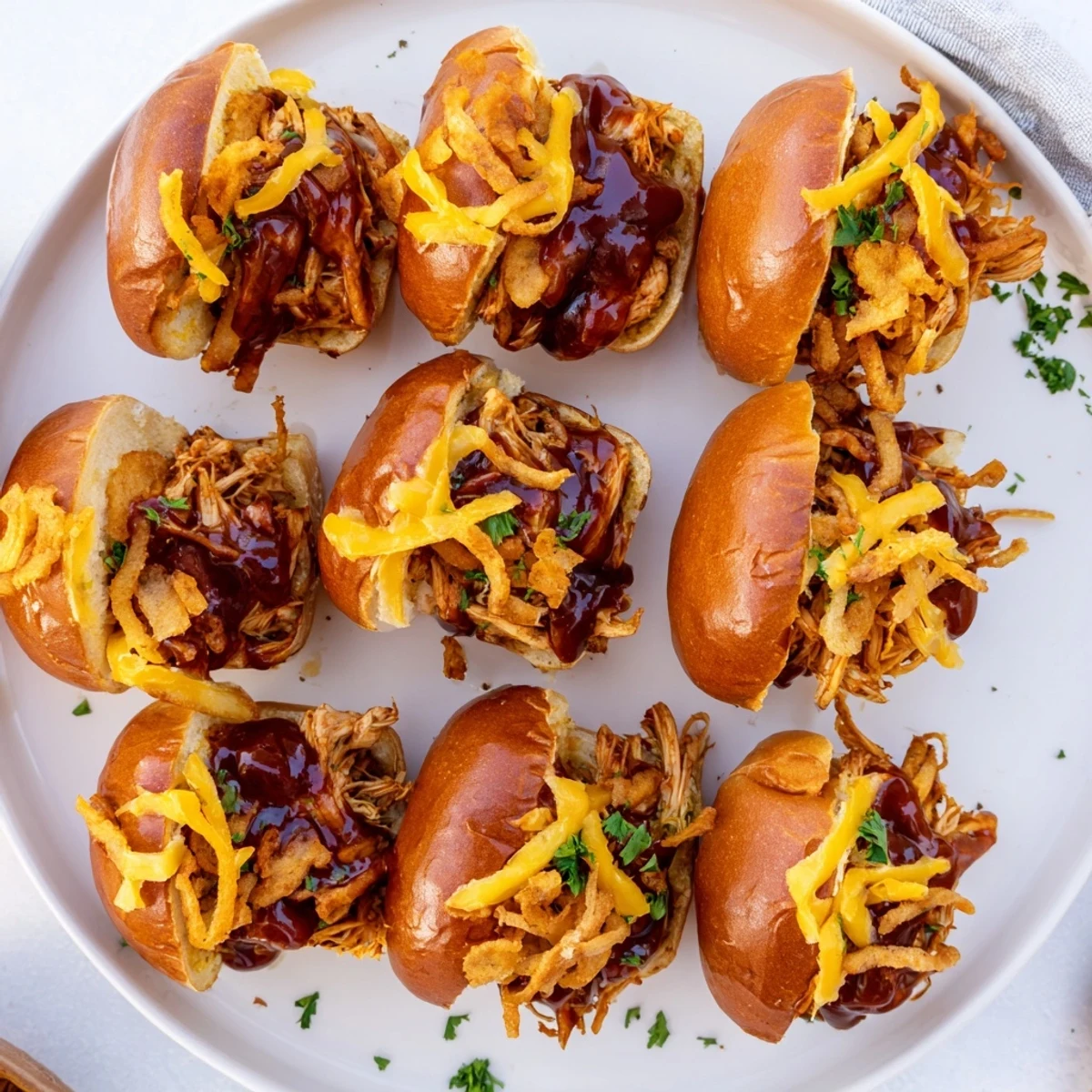 Savory barbecue shredded chicken sliders piled high with cheese and crunchy onions, perfect for game day parties
