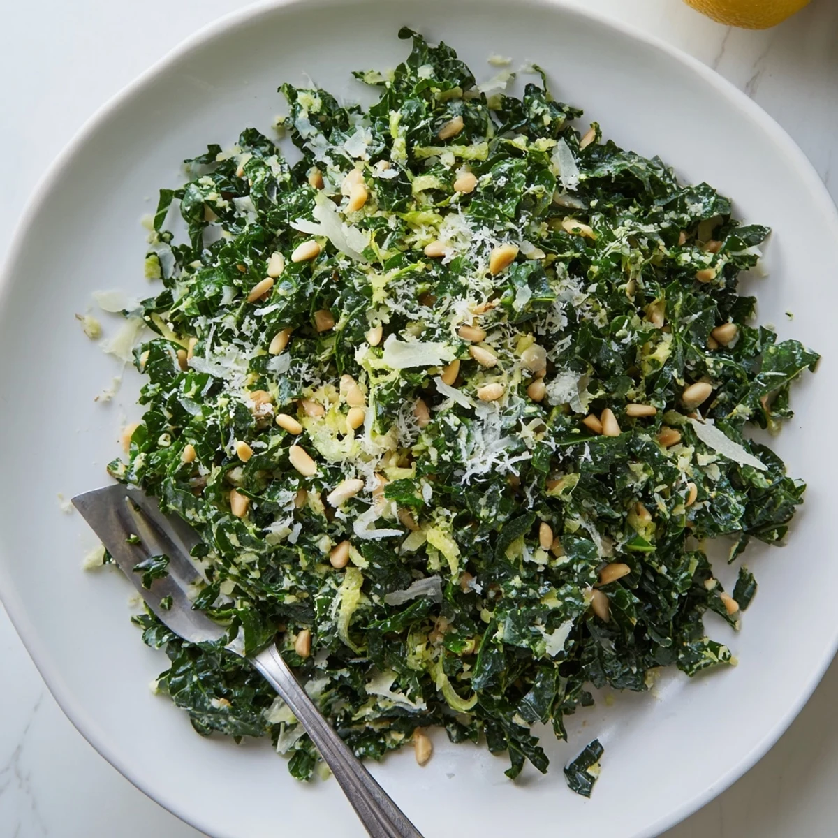 Bright garlic lemon Parmesan kale salad in a rustic wooden bowl with pine nuts