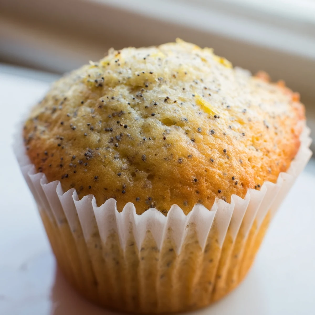 Moist lemon poppy seed muffins speckled with zest and seeds served on a rustic plate