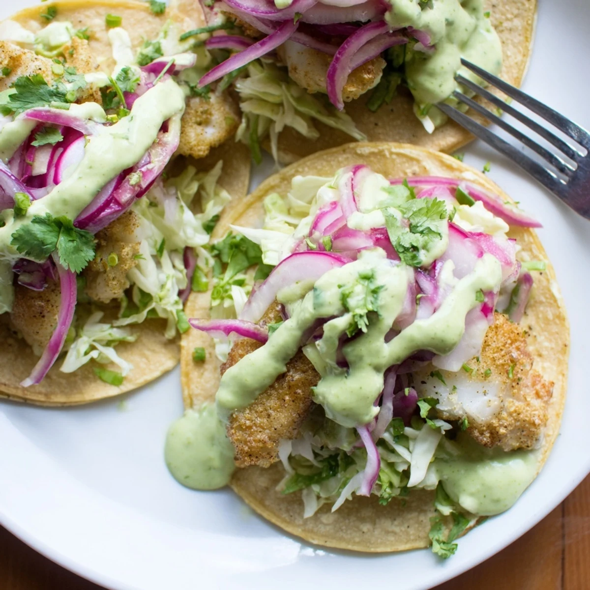 Baja Fish Tacos loaded with crunchy cabbage slaw and a generous swirl of avocado crema