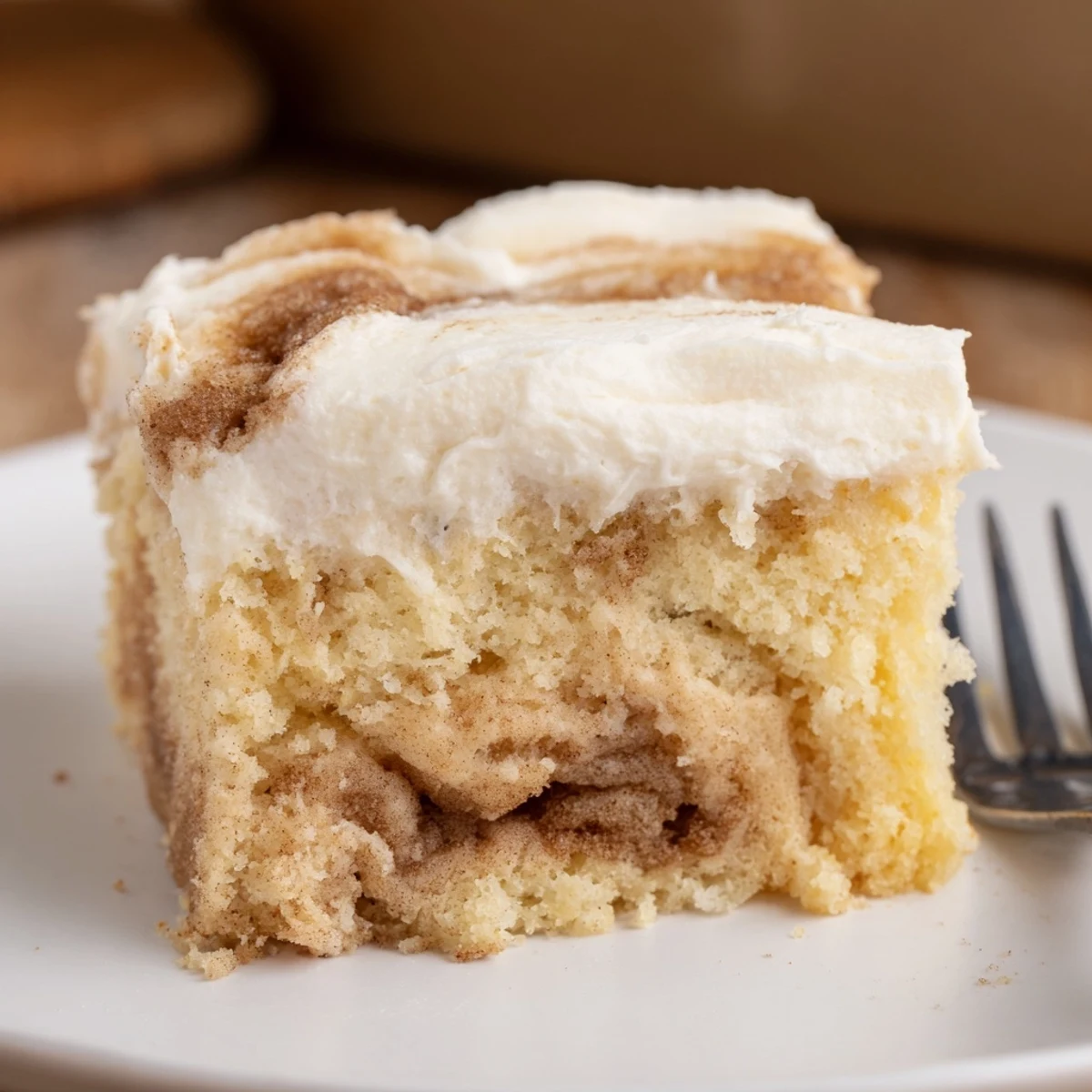 Cinnamon Roll Poke Cake with gooey cinnamon pockets and cream cheese frosting