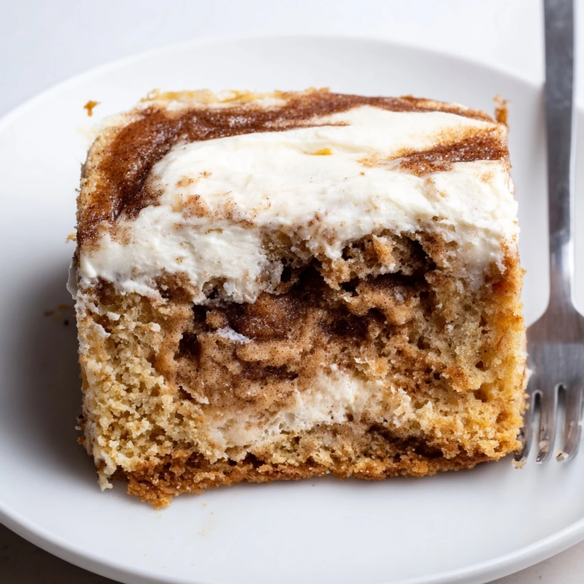 Warm Cinnamon Roll Poke Cake sliced for brunch, aromatic swirls and icing