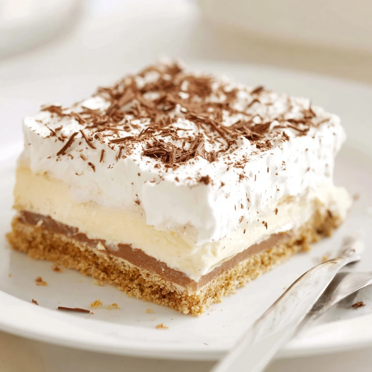 Glass dish of No Bake Layered Dessert showing smooth pudding and fluffy cream