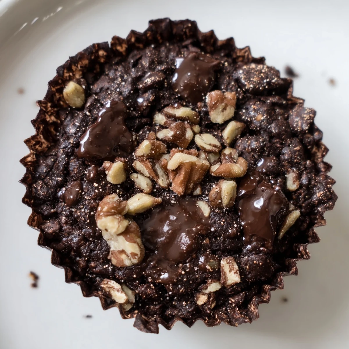 Fudgy dark chocolate oatmeal cupcakes sprinkled with sea salt, served on a white plate with a glass of milk