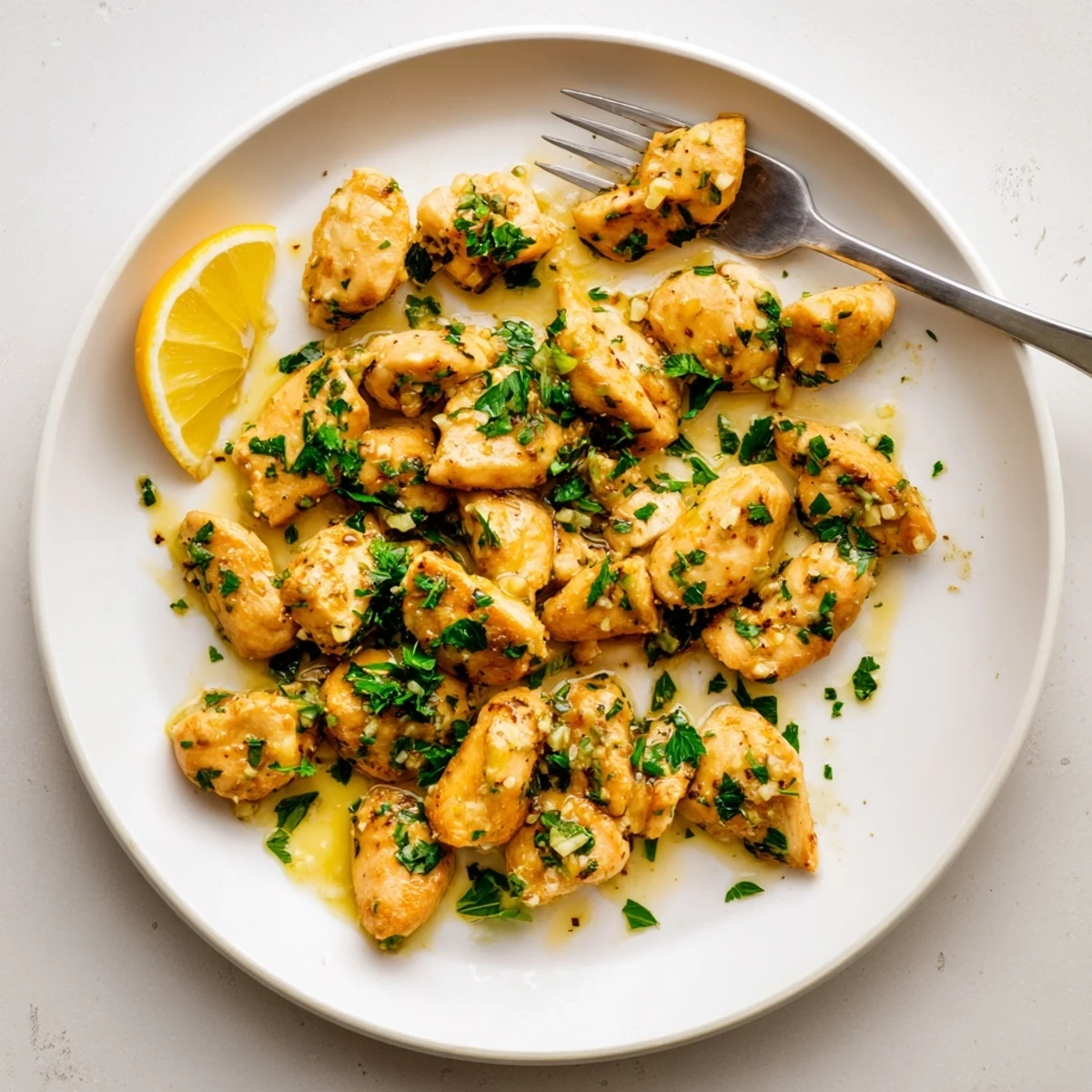 Golden brown garlic butter chicken bites garnished with fresh parsley in a white serving bowl