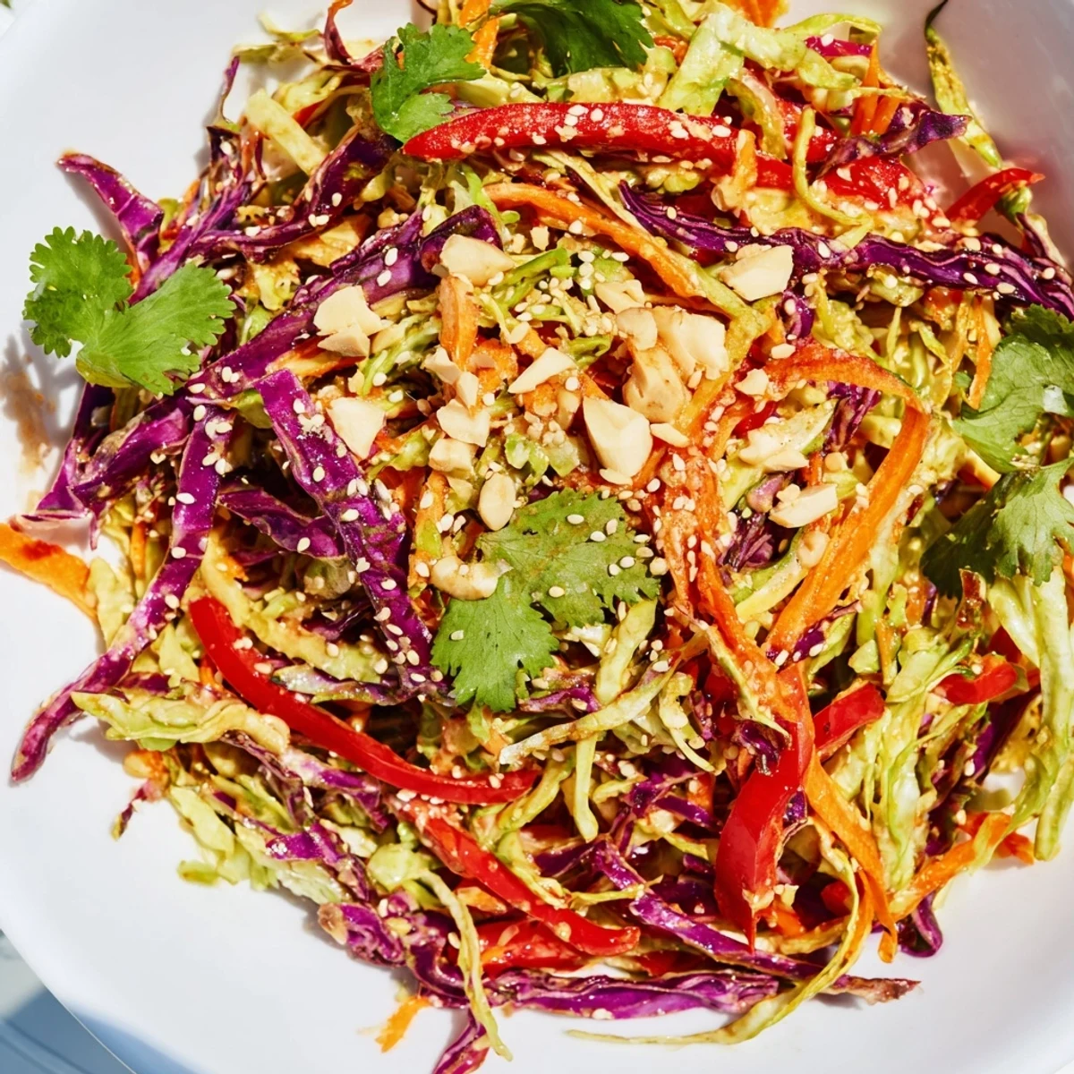 Colorful bowl of Asian cabbage salad featuring julienned carrots and bell pepper in sesame ginger dressing.