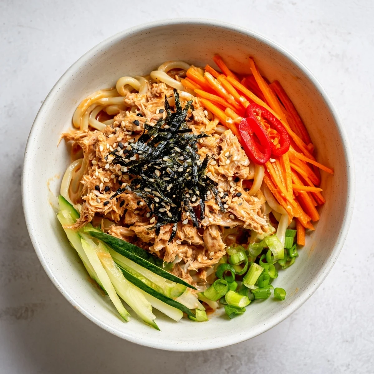 Savory tuna and udon noodles coated in creamy spicy mayo with toasted sesame