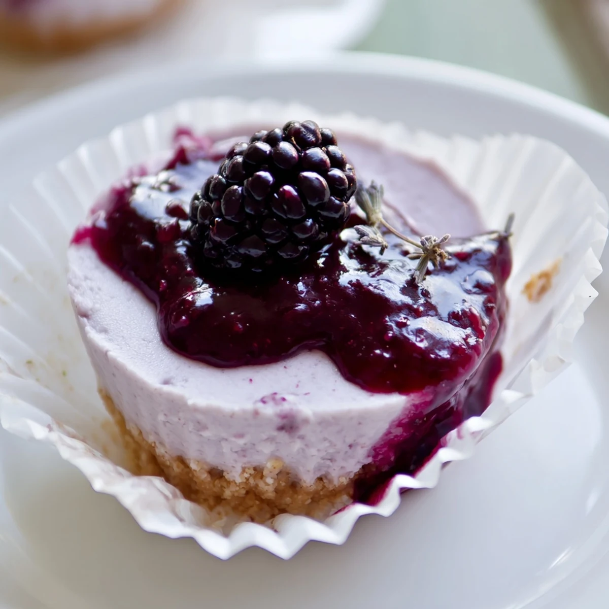 Silky no bake mini blackberry lavender cheesecakes in paper liners with fresh blackberry garnish