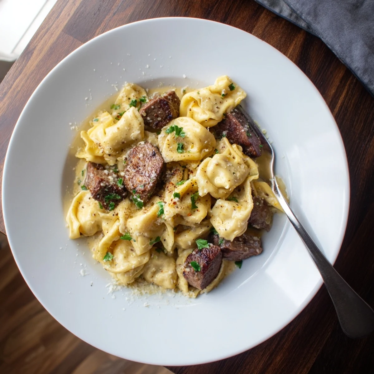 Close-up of garlic steak tortellini tossed in a velvety parmesan cream sauce with steak pieces