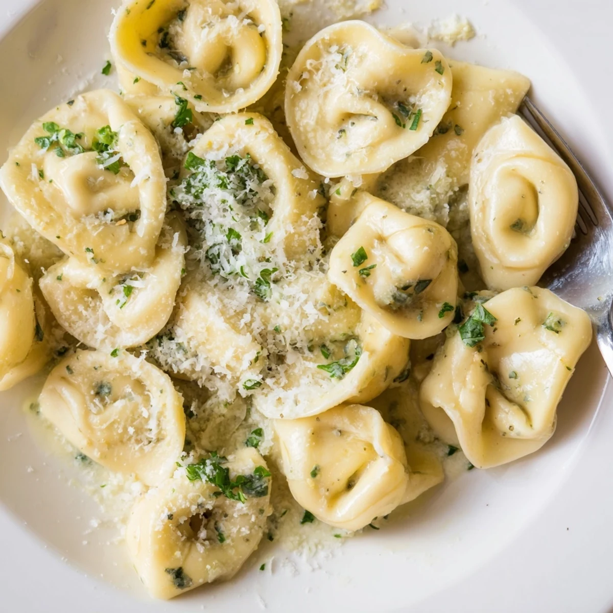 Delicious chicken tortellini floating in a light buttery cream sauce, topped with grated Parmesan and herbs.