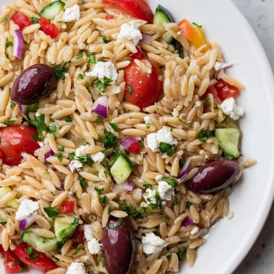 Bright Mediterranean Orzo Pasta Salad featuring plump cherry tomatoes, briny olives, and fresh herbs